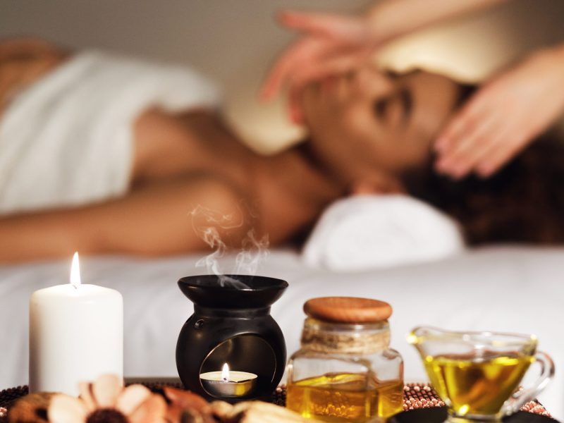 Aroma spa composition with candles and relaxing woman on background